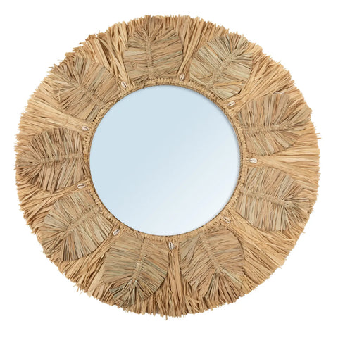 A round mirror with a decorative frame made of woven raffia and leaves, elegantly styled in a sunburst pattern. The inclusion of natural fibers gives it a bohemian and rustic appearance, while the subtle addition of cowrie shells adds an extra touch of coastal charm.