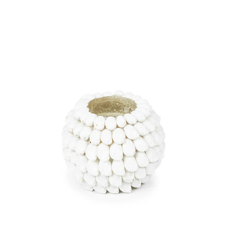 A small, round, decorative white candle holder is adorned with a textured pattern resembling clustered pebbles. The interior is hollowed out to hold a candle, perfect for casting a boho light. The background is plain white.