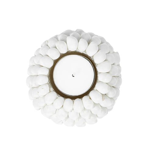 A coastal tealight holder viewed from above, featuring a central white candle surrounded by small, white pebble-like decorations arranged in a circular pattern. The overall appearance is clean and minimalist, embodying a serene beach-inspired essence.