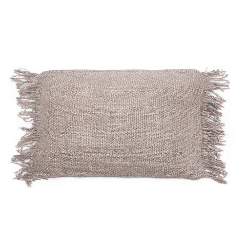 A textured beige cotton cushion with fringed edges on each side exudes a boho vibe. The woven material adds a rustic, cozy feel to any space. This charming accessory is set against a plain white background.