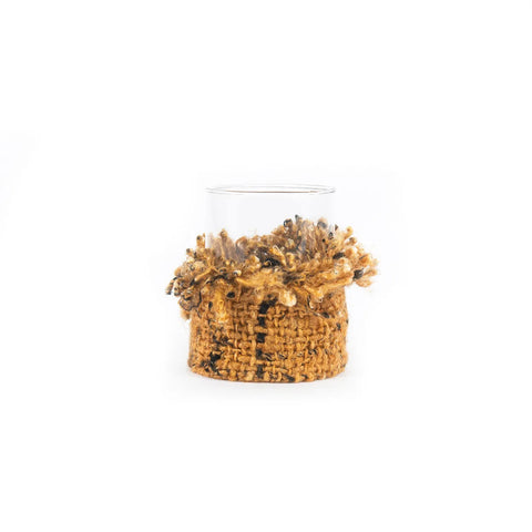 A clear glass container with a decorative handmade base made from woven jute and small shells, perfect as a rustic candle holder for your home decor. The jute and shells form a textured band around the bottom of the glass, adding to its natural charm.