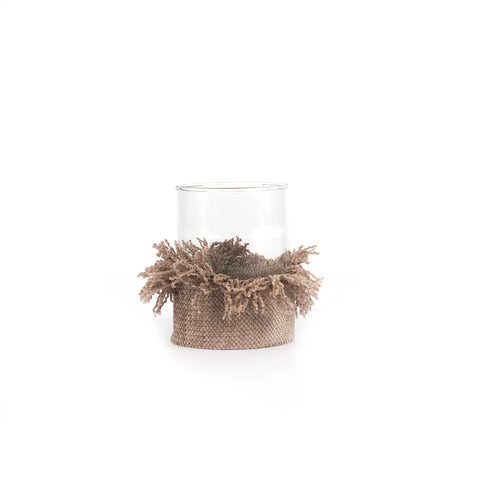 A clear glass vase with a burlap and fringe wrap at the base, reminiscent of delicate knitted cotton, set against a white background.