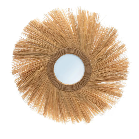 This round mirror, part of a limited edition collection, features a decorative frame crafted from natural brown fibers that radiate like sun rays. The fibers create a textured, rustic appearance, perfectly embodying a bohemian style.