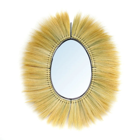 The Royal Mirror features a circular design with an intricate wooden frame resembling sun rays, crafted from light brown bristles and natural grass. This boho touch adds texture and warmth to the reflective surface, creating a truly organic appearance.