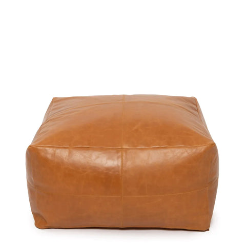 A square, brown nappa leather pouf with visible stitching on its surface rests against a plain white background. Its smooth texture and minimalist design suggest a contemporary style, making it the perfect luxury accessory for any modern space.