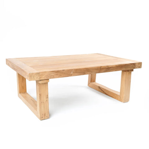 A rectangular teak coffee table with a simple, minimalist design. It features a light natural wood finish and sturdy block legs. The table has a smooth surface and geometric lines, giving it a modern yet rustic appearance.